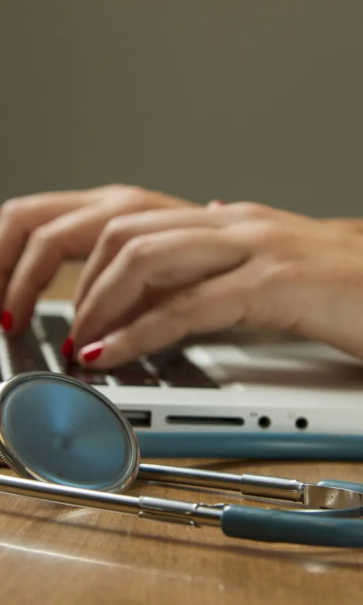 Stethoscope resting beside a laptop during a consultation