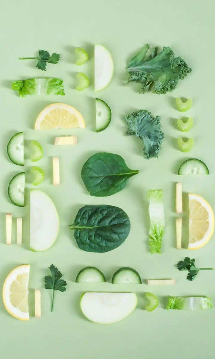 Fresh greens, cucumber and lemon slices arranged on a pale green surface