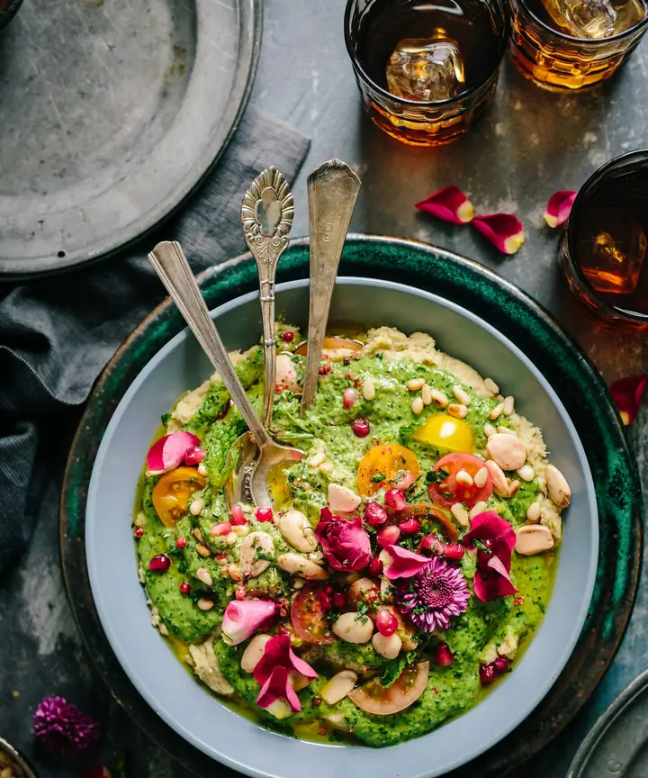 Green grain bowl topped with nuts and edible flowers