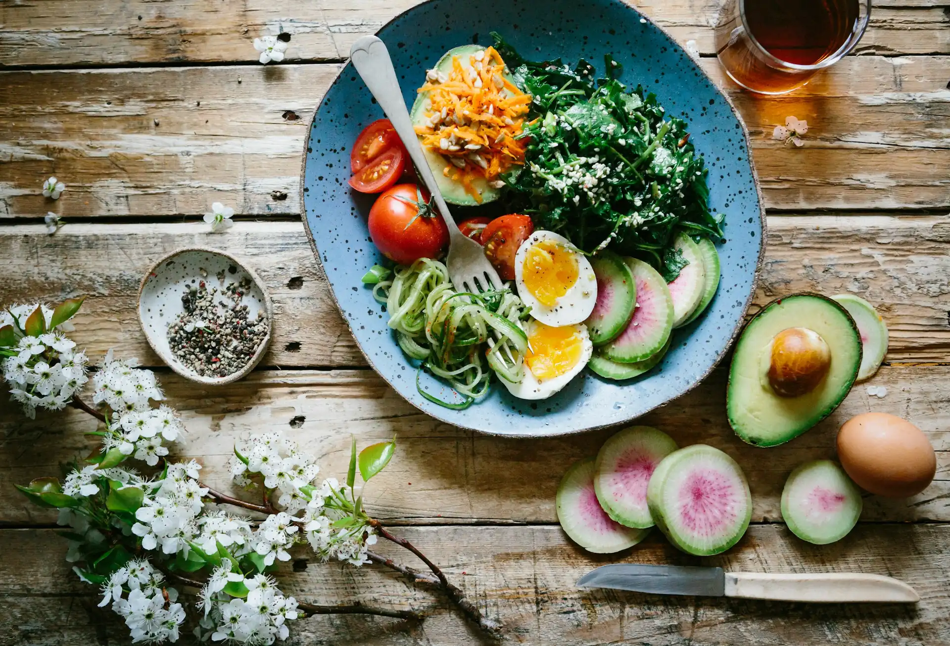 Balanced meal bowl with vegetables, egg and avocado on a wooden table
