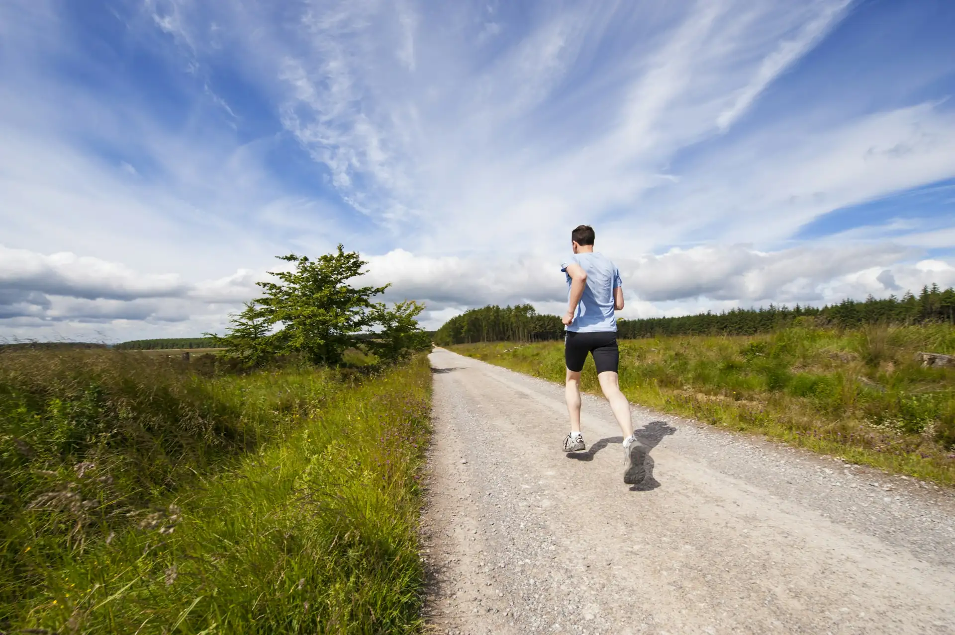 Person jogging along an open trail under a wide sky